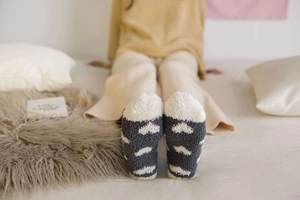 Detail showing the thick coral fleece texture and white heart pattern of warm winter socks