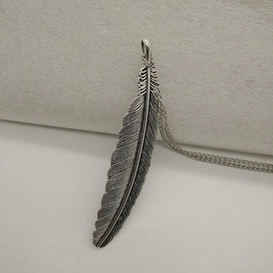 Detailed close-up of retro silver feather pendant necklace with vintage metallic texture
