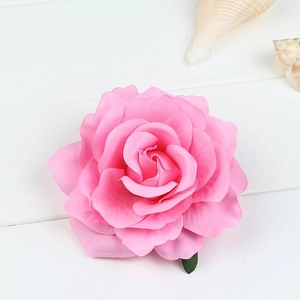 Detailed top view of realistic pink fabric rose hair clip on a white wooden background