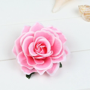 Detail of pink artificial silk rose hair clip on a white wooden background with a seashell