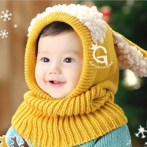 Detail of baby winter knit hat with earflaps and lamb wool trim in ginger yellow