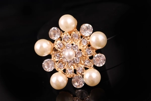 Dettaglio macro di spilla a fiore con perle color crema e strass luccicanti