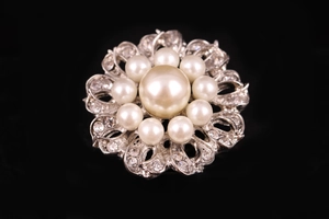 Dettaglio della spilla a fiore argento con perle bianche e strass di cristallo trasparente