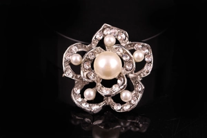 Dettaglio spilla a forma di fiore in argento con cristalli e perla centrale