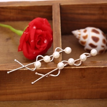 Detail of silver wavy hair clips with white pearls resting on a wooden vintage box