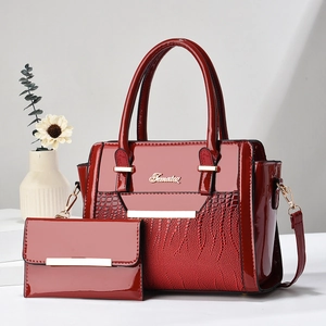 Detail of red patent leather tote bag set with crocodile embossing and golden metal hardware