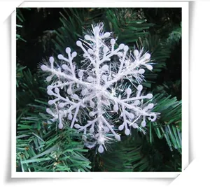 Close-up of a white glitter snowflake ornament hanging on a green Christmas tree branch