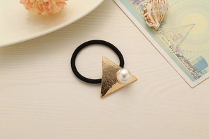 Detail of elastic hair tie with gold triangle metal and white pearl on wood