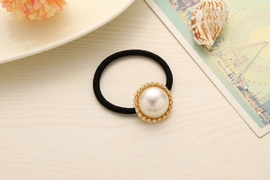 Close-up of elegant hair tie with large faux pearl in golden textured setting