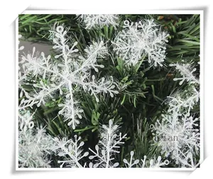 White snowflake ornament with glitter finish on green pine branches for Christmas decor