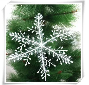 Detailed view of white glitter snowflake ornament on a green Christmas tree branch