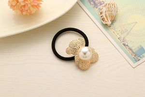 Close-up of black elastic hair tie featuring a golden bear charm with a pearl inlay