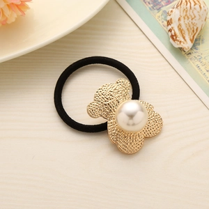 Elastic hair tie with a golden bear charm and large white pearl on a beige surface