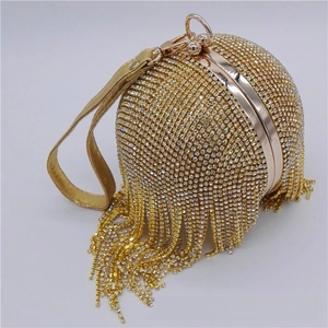 Close-up of golden spherical evening bag featuring dense rhinestones and long tassels