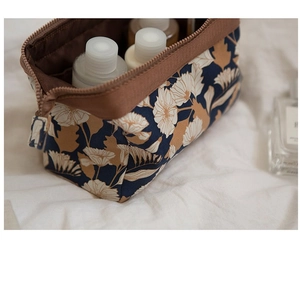 Detailed view of floral flamingo storage bag with cosmetics on soft white fabric