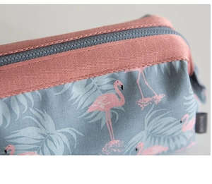 Close-up of blue fabric makeup bag with pink flamingo patterns and a pink zipper closure