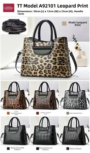 Detail view of large trapezoid handbag showing leopard print faux leather and dual handles
