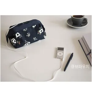Navy blue floral canvas travel pouch for makeup and electronics on a clean desk setup