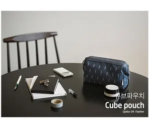 Close-up of a navy blue cube storage pouch with feather patterns and a side handle