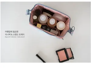 Macro view of light blue floral cube makeup bag with pink interior dividers and cosmetics