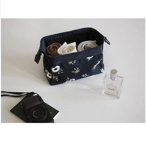 Deep blue floral canvas makeup bag showing spacious interior with rolled clothes inside