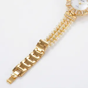 Close-up of luxury women's watch featuring a three-row pearl band and crystal bezel