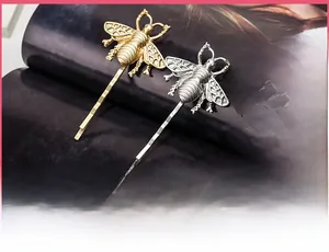 Detailed view of vintage matte gold and silver bee hair clips with hollow metal craft