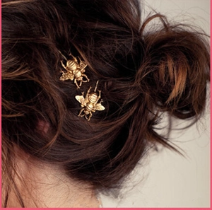 Detailed close-up of vintage matte gold bee hair clips styled on dark brown braided hair