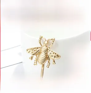 Detailed close-up of a matte gold bee hair clip showing realistic wing texture and carvings