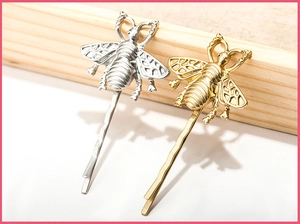 Detailed view of hollow vintage bee hair pins in matte gold and silver finishes