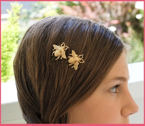 Detailed view of matte gold bee hair clips styled on long brown hair for a vintage look