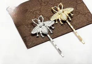 Detailed view of matte gold and silver honeybee hair clips with hollow wing textures