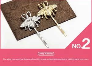 Detailed macro view of vintage matte gold and silver bee hair clips with alloy texture