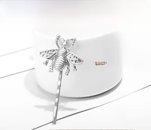 Detail of silver matte bee hair clip with hollow wings clipped on a white cup
