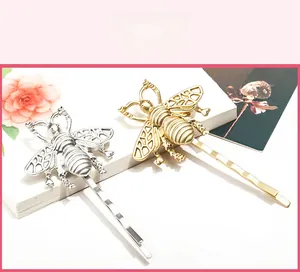 Detailed macro view of vintage bee hair clips in metallic gold and silver finishes