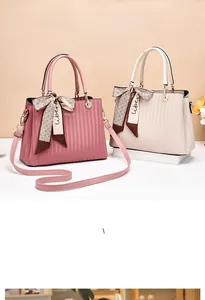 Detail view of pink and beige PU leather handbags with pleated texture and silk scarves