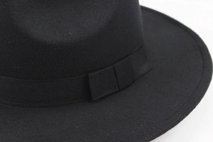 Close-up of black wool fedora with a matching grosgrain ribbon and folded detail