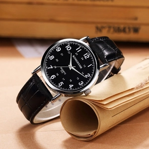 Detail view of quartz watch with black leather strap on a vintage wooden box
