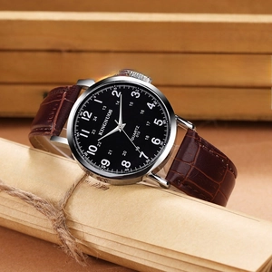 Close-up of brown crocodile leather strap and silver quartz watch on rustic background