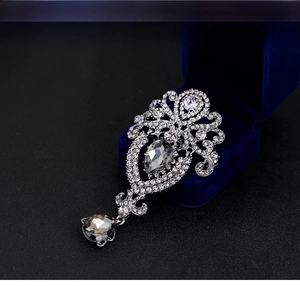 Macro view of vintage crown brooch featuring silver hollow patterns and grey crystal drops