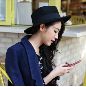Outdoor side view of a black wide-brim felt Fedora hat with matching ribbon detail