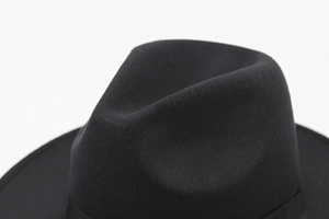 Close-up of a black wool fedora hat crown with classic ribbon detail and textured felt finish