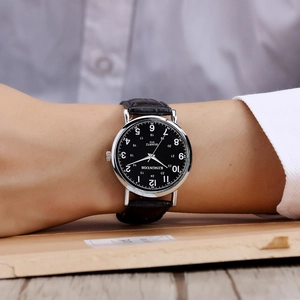 Close-up of black quartz watch dial with silver case on a model's wrist detail