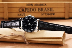 Macro detail of quartz watch featuring black leather strap and polished silver bezel
