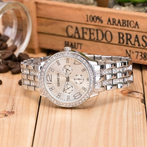 Close-up of Geneva silver metal watch with diamond accents and three-eye dial on wood
