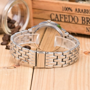 Detailed view of silver metal strap and Geneva quartz watch case back on wood