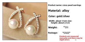 Détail de boucles d'oreilles croisées dorées avec perles blanches et strass étincelants