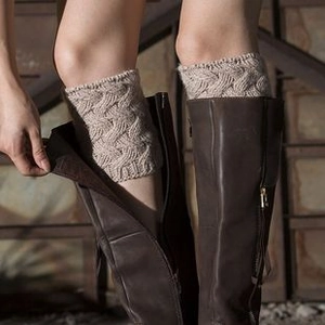 Detail of beige cable knit leg warmers with diamond pattern texture over boots