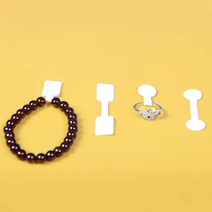 White adhesive jewelry tags for rings and bracelets shown on a bright yellow background