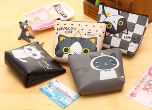 Detail view of four cute cartoon cat PU leather coin purses with zippers on a wooden table